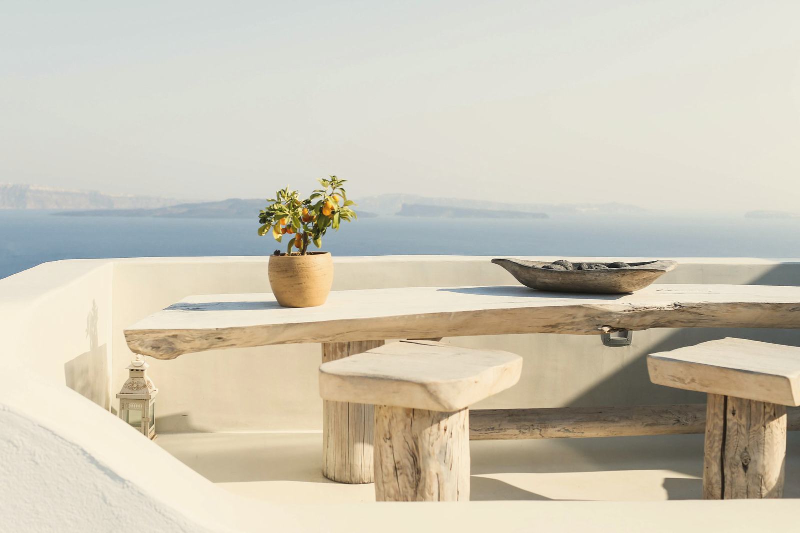 Weiße Terrasse mit Holzbank und Blick über die Ägäis
